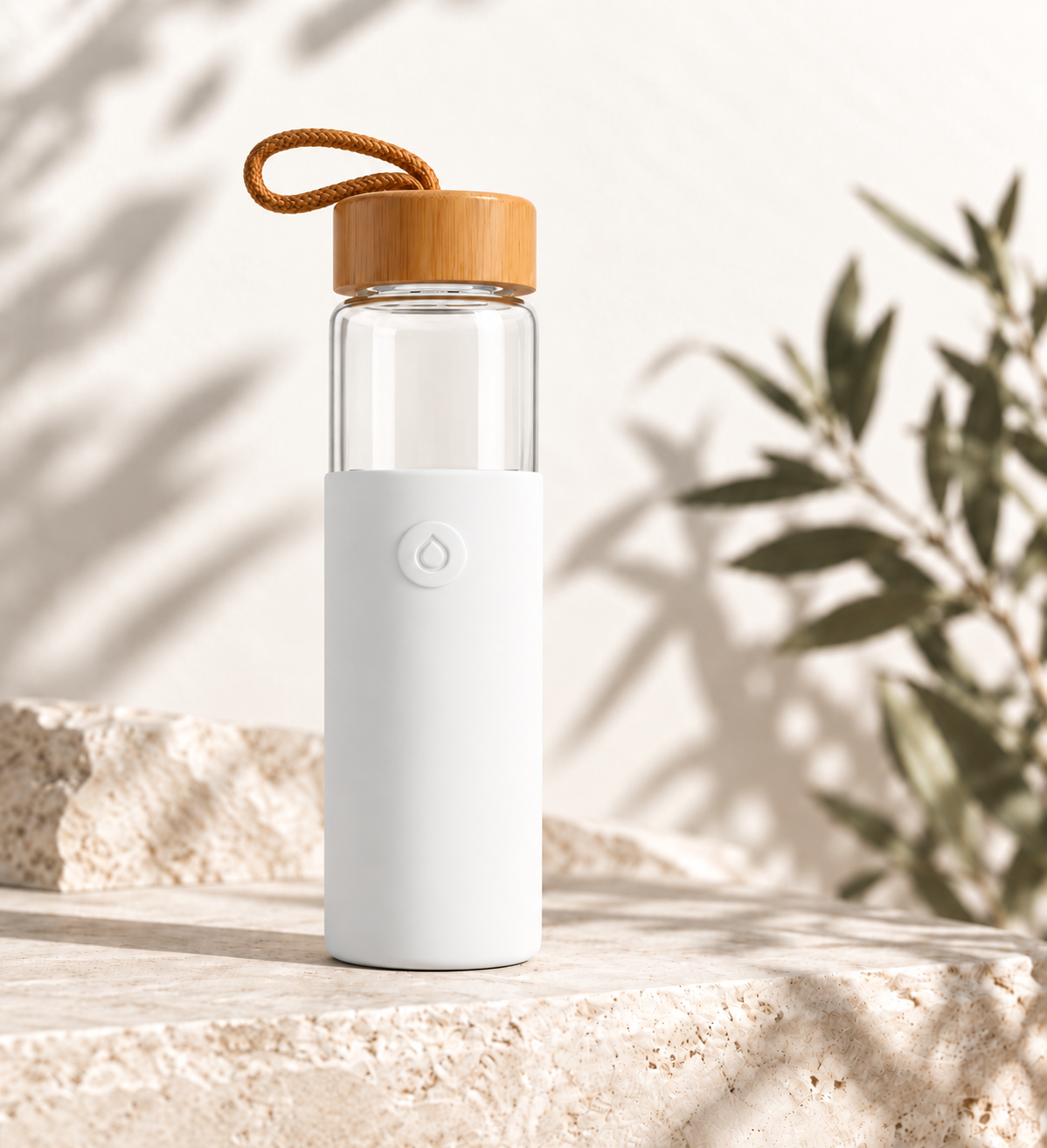 White Agua bottle with bamboo lid and carry loop on warm stone, with soft plant shadows