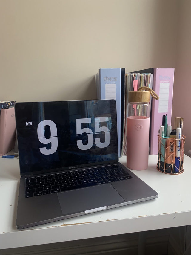 Pink bottle beside a laptop